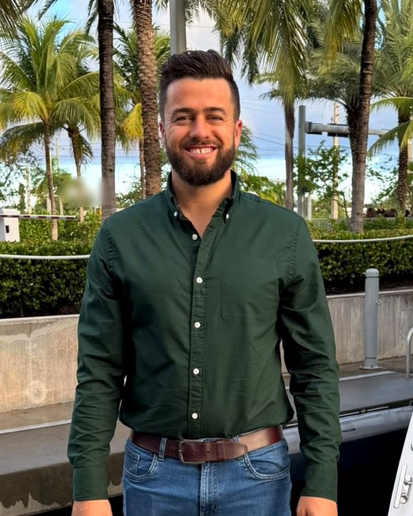 Damian Adcock smiling on a marina dock in Florida, with palm trees behind him.